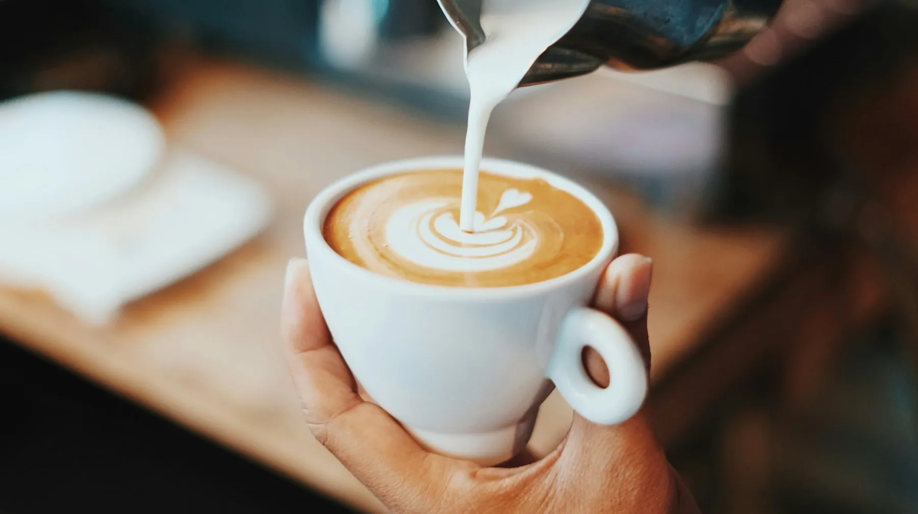 Fincandaki espressonun üzerine süt dökülerek latte art yapılıyor