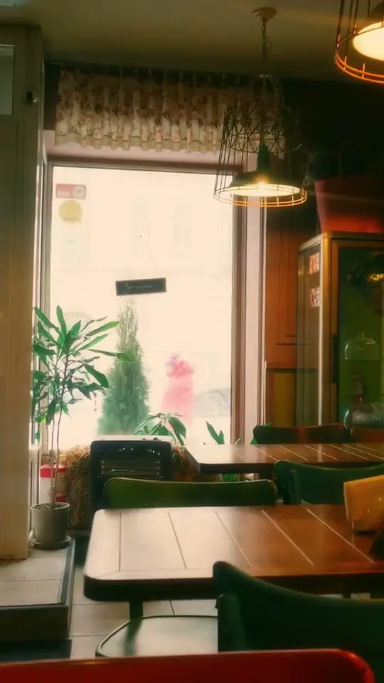 Ahşap masalı, sarkıt lambalı sakin bir kafe iç mekânı (temsilî)